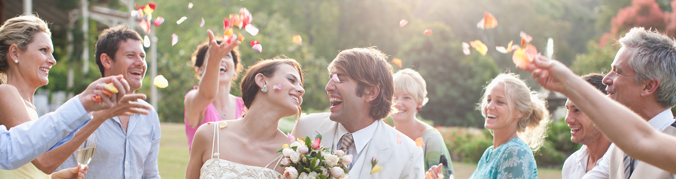 A couple getting married, smiling at each other, with confetti thrown at them from guests left and right