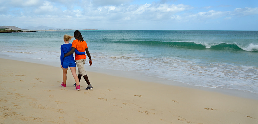 Couple strolling along a sandy beach looking out to sea in the Canary Islands