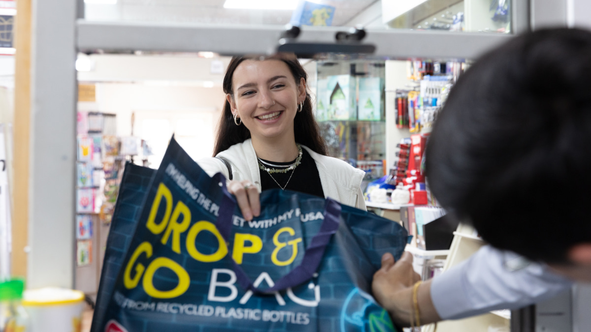 Female customer handing a Drop and Go back to a member of Post Office staff at a counter