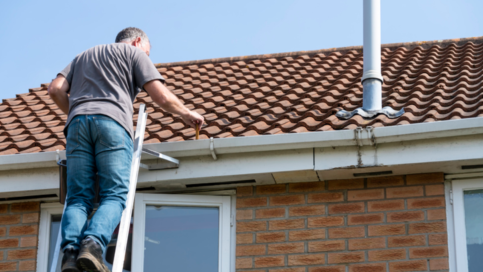 man clearing the gutter from the roof