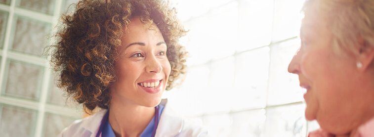 Female doctor smiling and talking to an elderly female patient