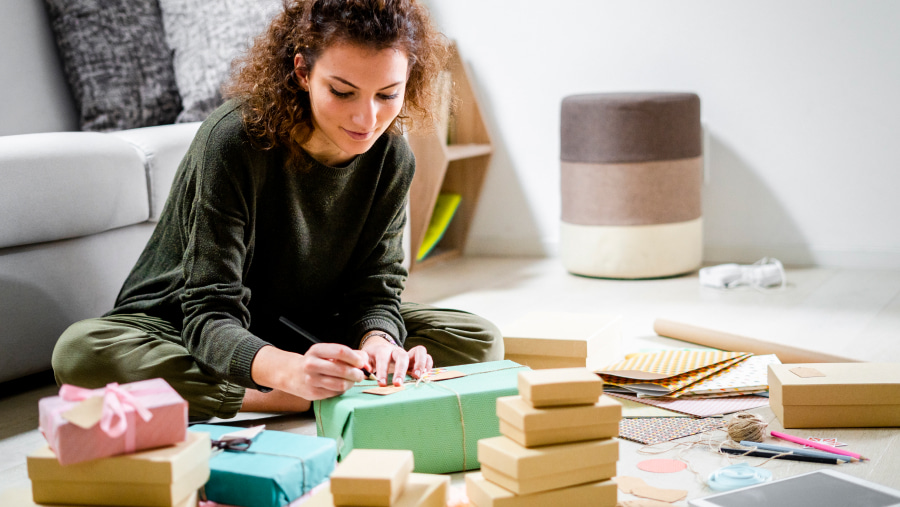 Woman sat on a lounge floor wrapping parcels of varying sizes