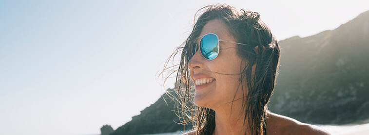 Woman wearing sunglasses and smiling with mountains in distance