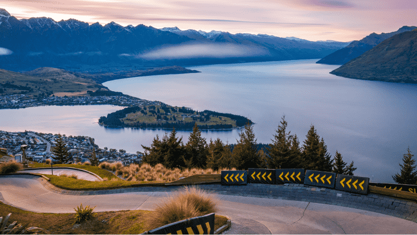 A river in New Zealand in the early evening, surrounded by winding roads & mountainous terrain