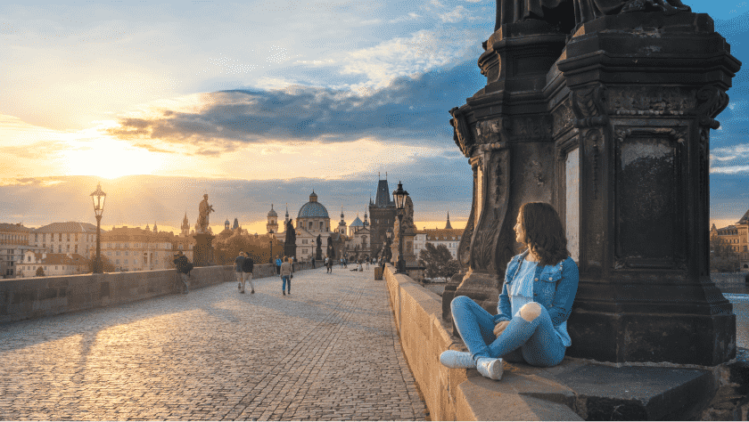 a person admiring the sunrise from the Charles Bridge in Prague