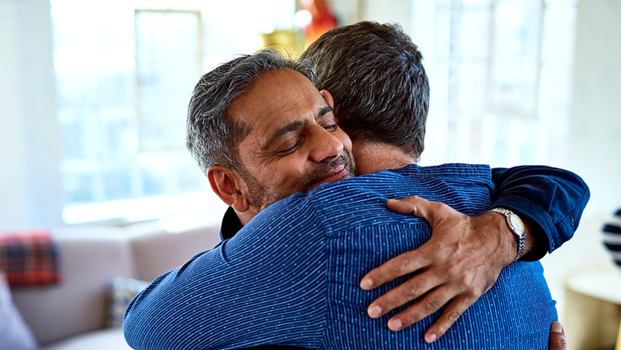 Older tanned male embracing another person with their back to us